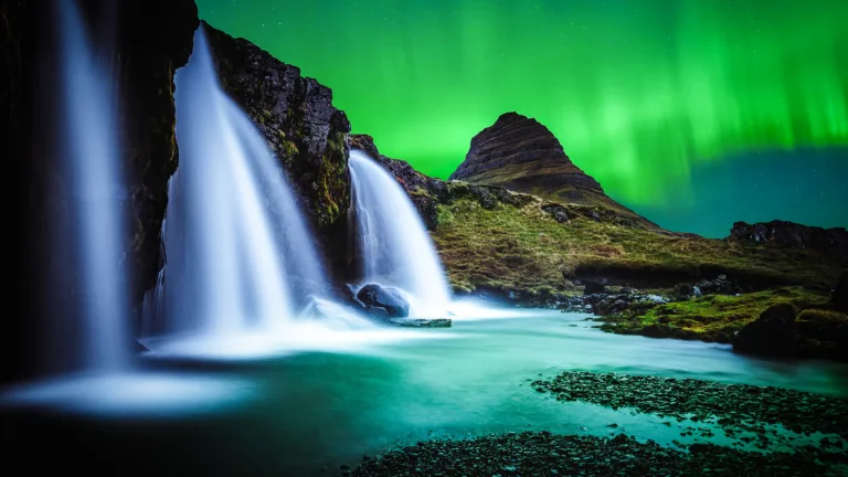 Enjoy the magical beauty of Iceland's Kirkjufell mountain illuminated by the stunning Northern Lights in 4K resolution. This breathtaking landscape scenery wallpaper captures the awe-inspiring natural wonder of the Aurora Borealis.
