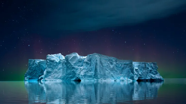 A breathtaking 4k wallpaper featuring an iceberg under a captivating aurora-filled sky. Experience the beauty of nature and the cold serenity of this stunning landscape.