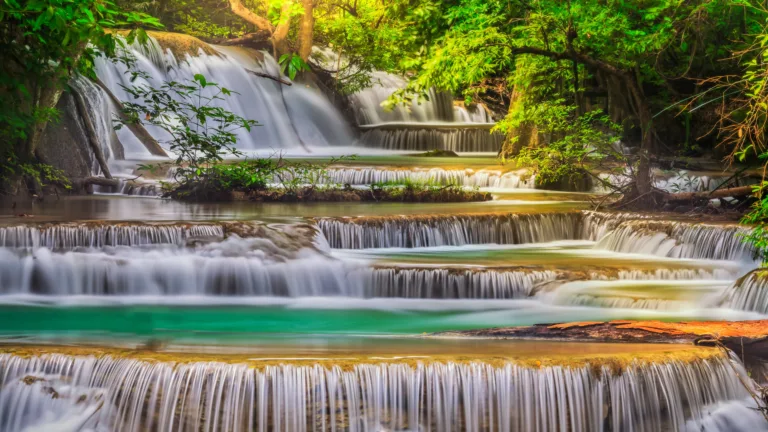 Immerse yourself in the natural beauty of Erawan Falls in Thailand with this captivating 4K wallpaper. The lush forest surroundings and cascading waterfalls create a scenic and tropical paradise that's perfect for travelers and those seeking a desktop background that captures the serene beauty of this stunning Thai destination.