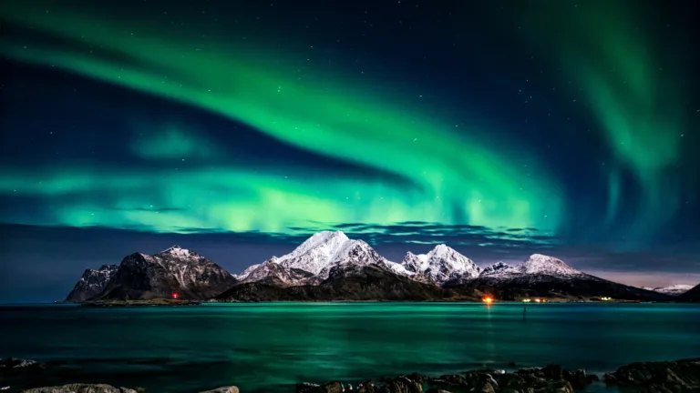 Behold the breathtaking beauty of the Northern Lights dancing above majestic mountains in this stunning 4K wallpaper. Experience the magic of the aurora borealis against the backdrop of a serene night sky. Perfect for nature enthusiasts and travelers seeking the celestial wonder of polar lights as a captivating desktop background.