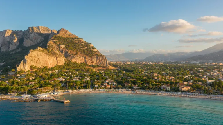 A breathtaking 4K wallpaper presents an aerial view of Mondello Beach, where the azure sea meets the sandy coastline under the Mediterranean sun. The drone-captured image showcases the stunning beauty of this Sicilian destination, making it an irresistible choice for your desktop or mobile wallpaper.
