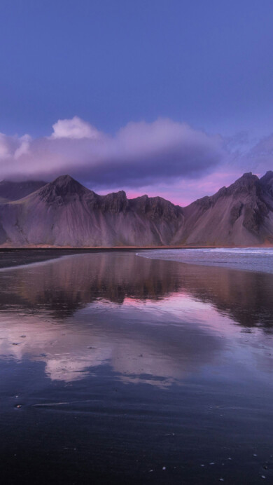 A mesmerizing 4K wallpaper capturing the majestic beauty of Vestrahorn Mountain reflected in calm waters. The tranquil scene depicts the towering mountain mirrored perfectly in the serene lake, showcasing the breathtaking landscape of Iceland. Ideal for adorning your desktop or mobile screen with nature's splendor.