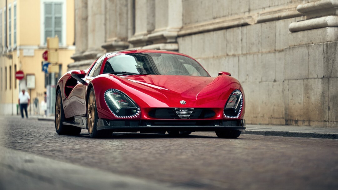A captivating 4K wallpaper featuring a magnificent Alfa Romeo 33 Stradale gleaming under focused illumination in a sophisticated showroom. The car's iconic silhouette, rendered in a deep, lustrous red, captures the essence of classic automotive design with striking light reflections along its elegant contours.