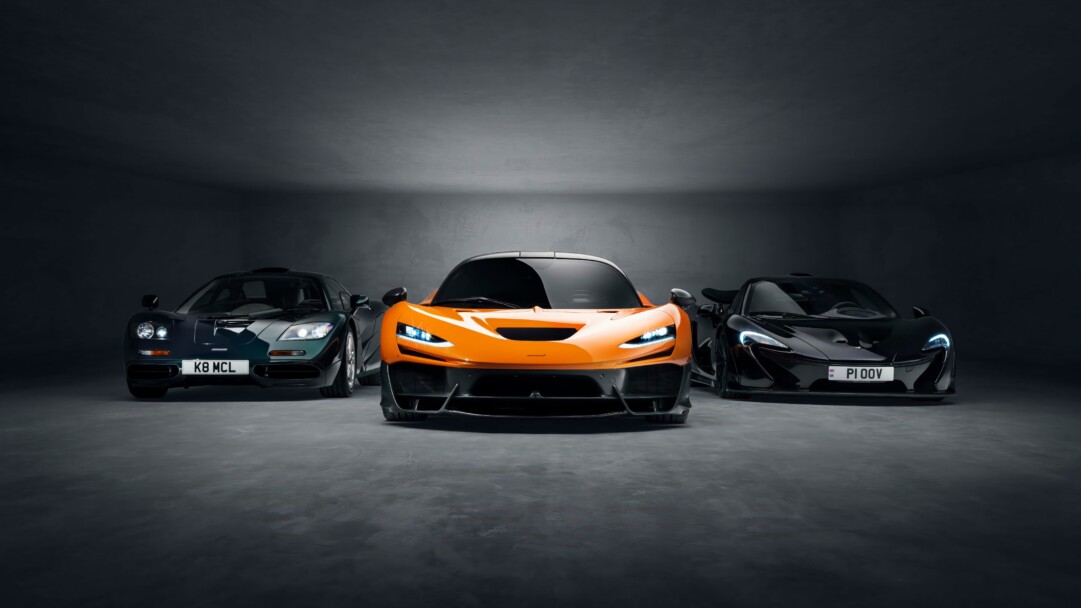 An exhilarating 4K wallpaper showcasing a lineup of high-performance McLaren supercars parked on a bright, smooth asphalt track under a clear sky. The vibrant, contrasting colors of the vehicles, bathed in sharp, directional light, accentuate their aggressive aerodynamic lines and convey a sense of immense speed and precision.