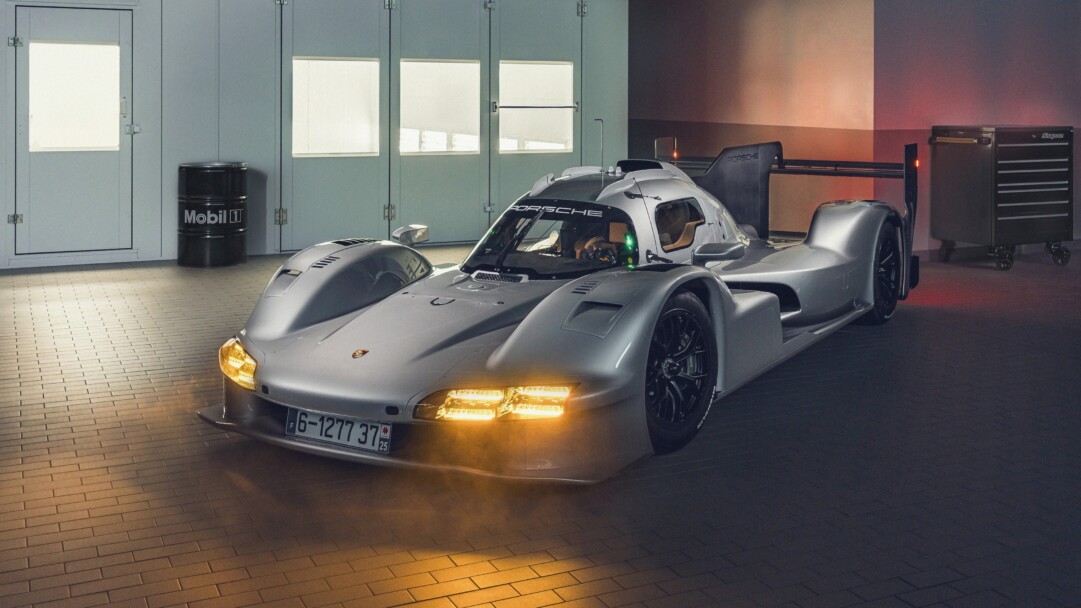 A sleek 4K wallpaper showcasing a pristine Porsche 963 Rsp LMDh prototype race car positioned dynamically on a dark, reflective surface, suggesting a studio or presentation setting. Its crisp white body with red and black accents gleams under bright, focused lighting, emphasizing its aerodynamic curves and cutting-edge design for a high-performance, futuristic feel.