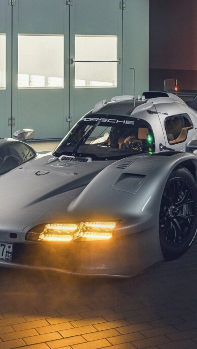 A sleek 4K wallpaper showcasing a pristine Porsche 963 Rsp LMDh prototype race car positioned dynamically on a dark, reflective surface, suggesting a studio or presentation setting. Its crisp white body with red and black accents gleams under bright, focused lighting, emphasizing its aerodynamic curves and cutting-edge design for a high-performance, futuristic feel.