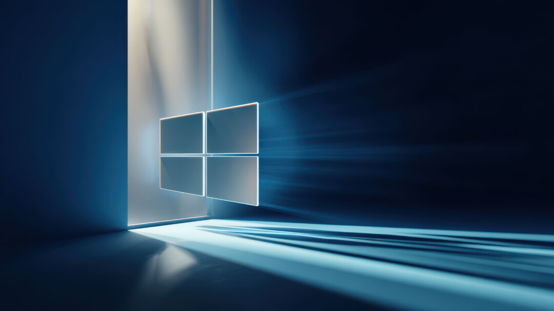 An ethereal 4K wallpaper portraying the modern Windows logo as four glowing, semi-transparent panes set within a dark, abstract blue chamber. Striking beams of light emanate from the left, illuminating the logo and creating dramatic horizontal light trails and reflections across the deep blue floor.