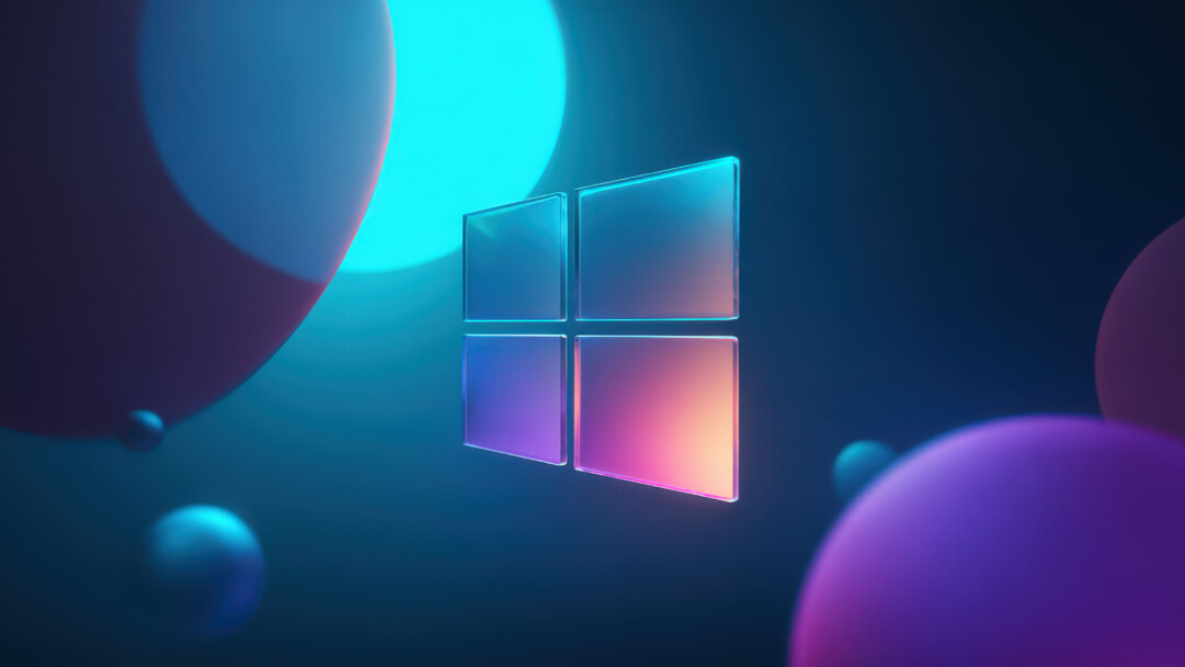 A mesmerizing 4K wallpaper showcasing a sleek, translucent Windows logo floating centrally in a dark, abstract digital space. The logo's glassy surfaces brilliantly refract light, displaying a spectrum of blues, purples, and warm oranges, creating an energetic and futuristic ambiance amidst floating, glowing spheres.
