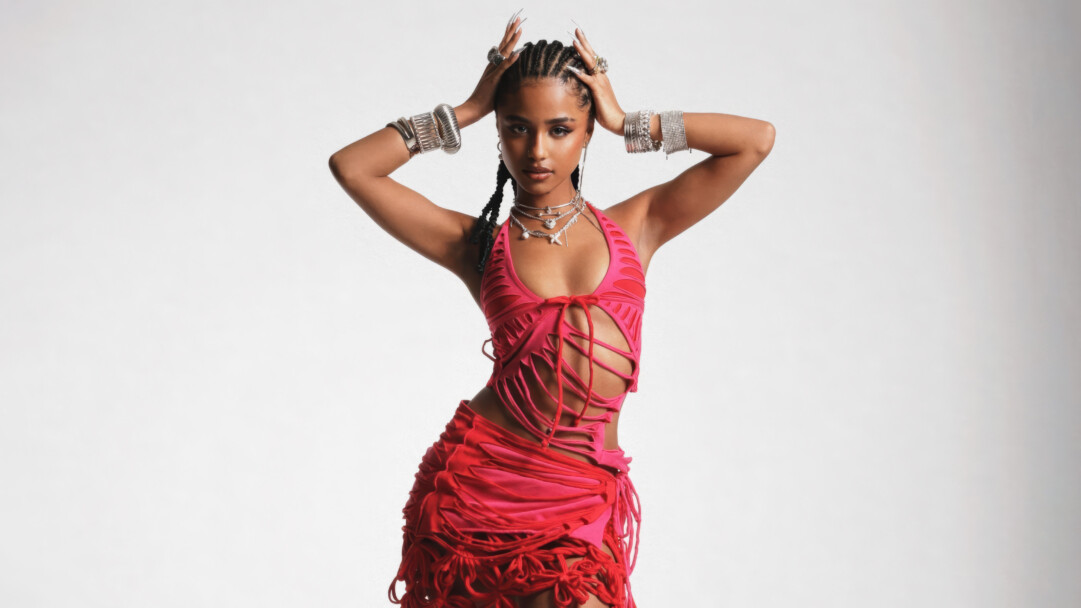 A captivating 4K wallpaper features Tyla, the celebrity, striking a dynamic pose against a minimalist white backdrop. Her stunning pink dress with intricate cutouts, complemented by an array of bold silver jewelry, perfectly accentuates her confident and stylish presence.