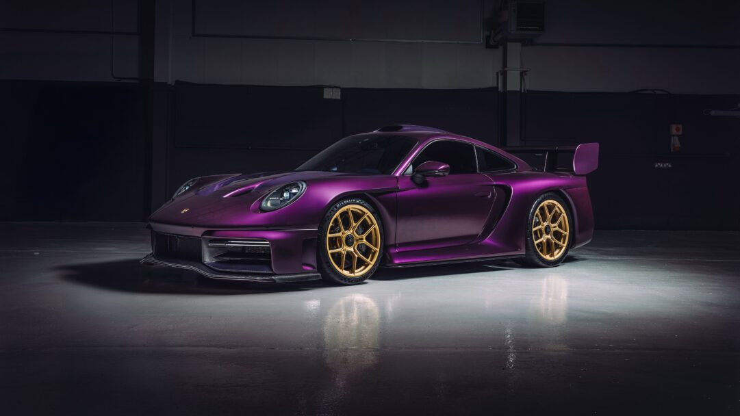 A breathtaking 4K wallpaper showcases a custom Porsche 911 Turbo S positioned in a dimly lit, minimalist studio environment. Its distinctive matte purple paintwork, perfectly complemented by the gleaming gold multi-spoke wheels, creates a luxurious and powerful visual contrast.