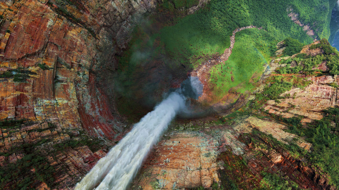 An immersive 4K wallpaper presents an aerial view of the majestic Churún Merú Waterfall in Venezuela, plunging into a deep, verdant canyon. The powerful white cascade dramatically contrasts with the rich red and orange stratified rock walls on one side and lush green foliage blanketing the other, leading to a winding river below.