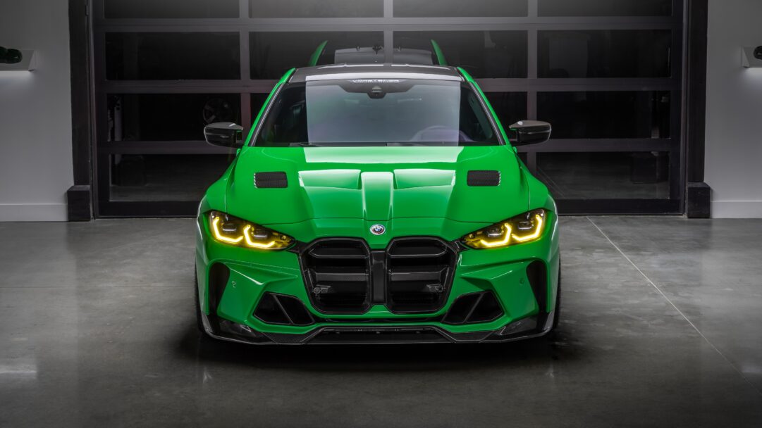 An intense 4K wallpaper showcasing a vibrant green BMW M4 GTS Vorsteiner, prominently displayed head-on within a sleek, dimly lit garage. Its fierce stance is accentuated by bright yellow LED headlights and intricate carbon fiber bodywork, creating a powerful, high-performance aesthetic.