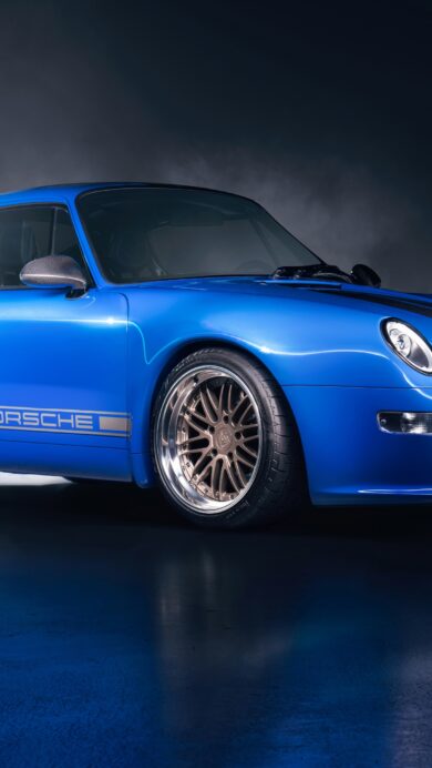 An exhilarating 4K wallpaper features a brilliant blue Porsche 911 Gunther Werks 400R Coupe, parked dramatically in a dark, smoky studio setting with a reflective floor. The car's vibrant paint and striking bronze wheels gleam under intense spotlights, while atmospheric smoke swirls around its form, creating an impactful, high-performance aesthetic.