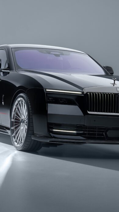 An exquisite 4K wallpaper presenting a sleek black Rolls-Royce Spectre EV luxury car, positioned angled in a minimalist, light grey studio setting. Its glossy black body reflects the pristine lighting, highlighting the illuminated grille, bright headlights, and intricate chrome wheels that emphasize its modern opulence.