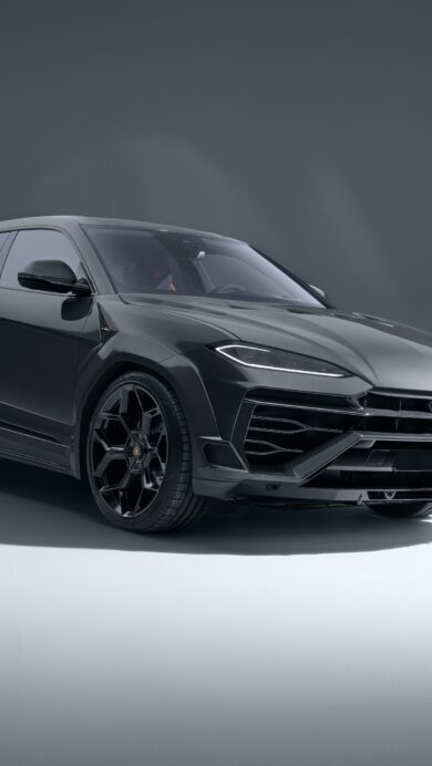 An opulent 4K wallpaper featuring a dark grey Lamborghini Urus SUV, posed in a sleek, minimalist studio environment. Dramatic lighting highlights the vehicle's aggressive front fascia and sharp contours, creating a sophisticated and powerful aesthetic.