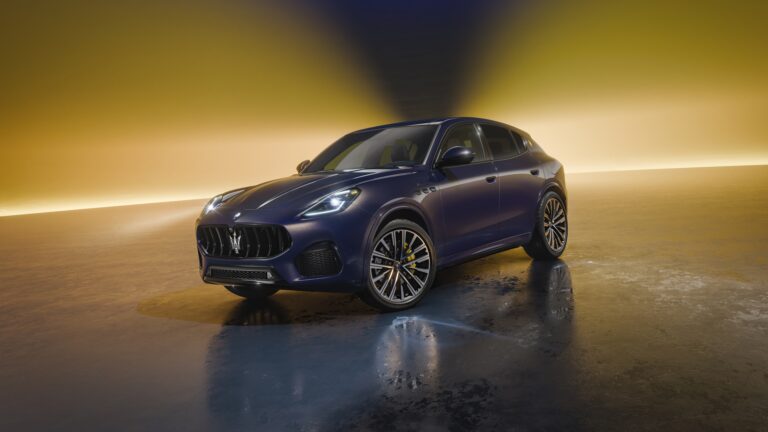 A captivating 4K wallpaper showcasing a dark blue Maserati Grecale SUV, angled slightly right, parked in a dimly lit studio against a striking golden backdrop. Dynamic golden light streams from behind, reflecting off the car's sleek body and creating a dramatic, wet-look sheen on the dark, reflective floor, emphasizing its powerful and luxurious presence.