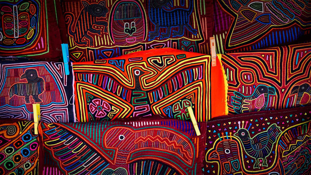 A kaleidoscopic 4K wallpaper of Guna Yala Mola Art features a vibrant display of traditional indigenous textiles, meticulously crafted and layered, showcasing an array of animals and geometric patterns. Each panel bursts with intricate, multi-layered appliqué and reverse appliqué techniques, creating a rich tapestry of fluorescent outlines and deep hues that convey a lively cultural heritage.