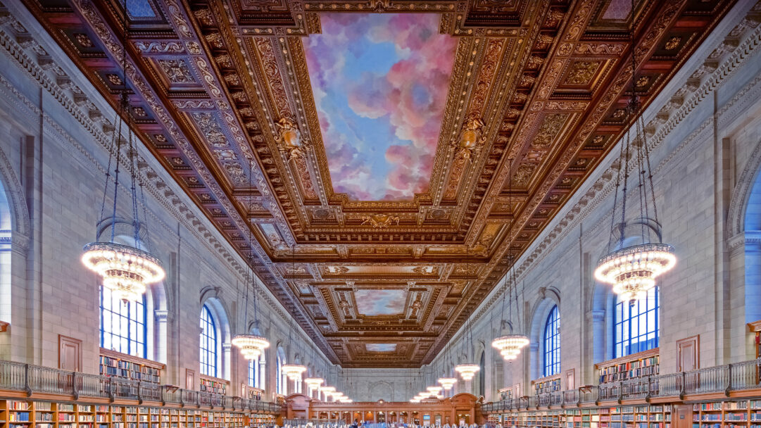 An awe-inspiring 4K wallpaper showcasing the grand, renovated Rose Main Reading Room of the New York Public Library, a vast hall lined with towering bookshelves and numerous elegant chandeliers. Its centerpiece is an exquisitely ornate ceiling, featuring rich golden carvings and a stunning central mural depicting a vibrant sky with pink and blue clouds, creating a sense of boundless majesty.
