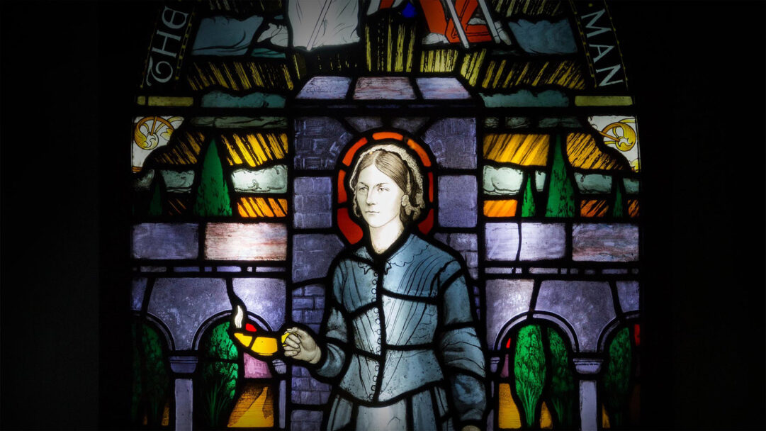 A timeless 4K wallpaper showcasing a meticulously painted leaded stained glass window panel, featuring a solemn woman holding an oil lamp at its center. The vibrant interplay of light through the rich blues, greens, and yellows of the glass creates a profound, glowing effect, emphasizing the intricate lead work and the warm illumination from the lamp.